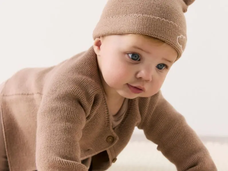A baby wearing a brown outfit and hat