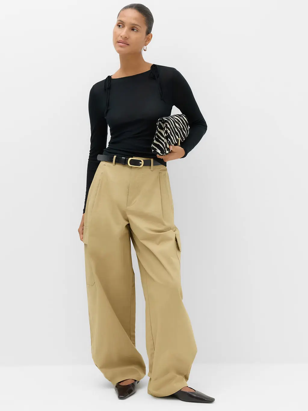 Woman in black top and tan trousers