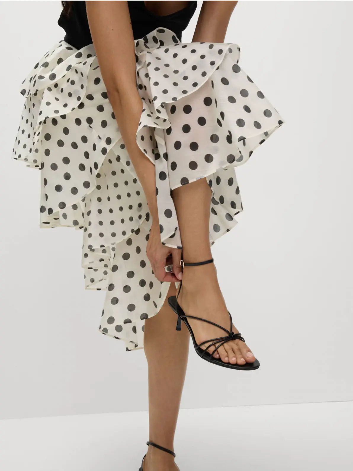 Woman wearing polka dot skirt and black strappy heels
