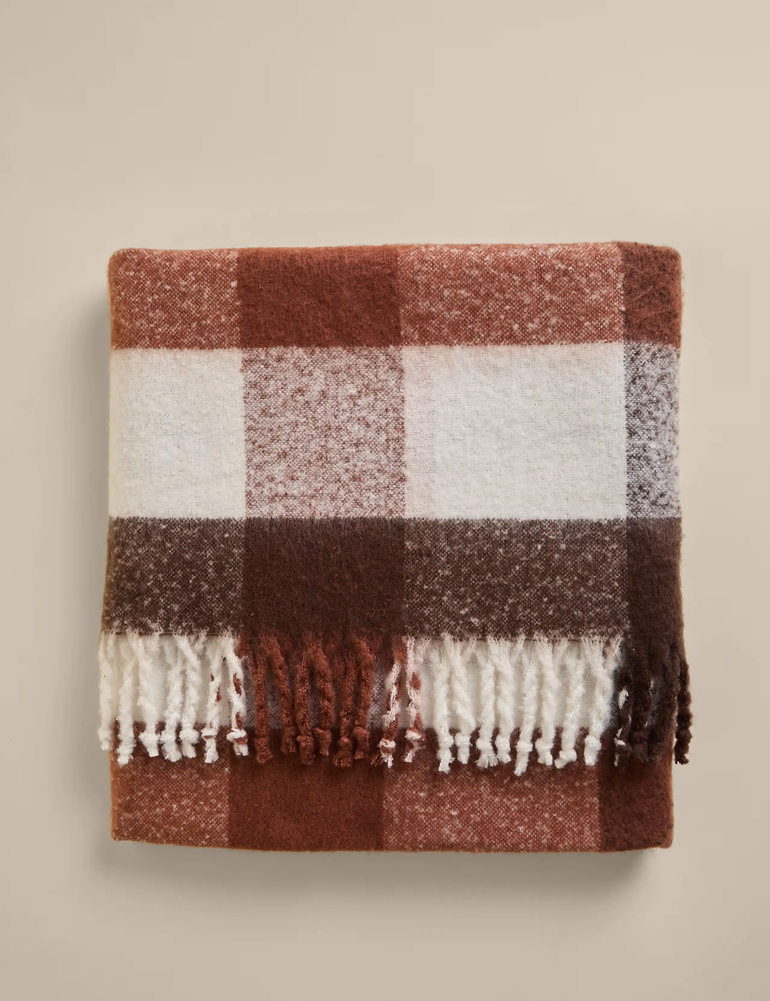 Checked throw with a white, brown and green pattern and tassel edging.
