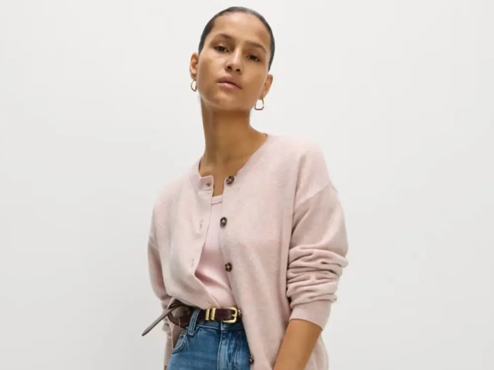 A woman wears a pink cardigan and pink top with jeans