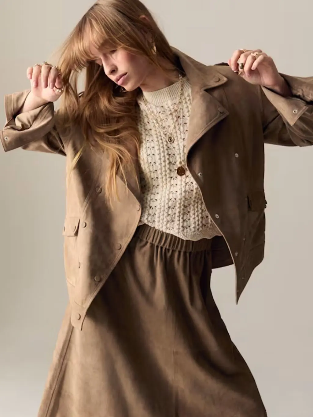 A woman wears a brown suede biker jacket and matching skirt
