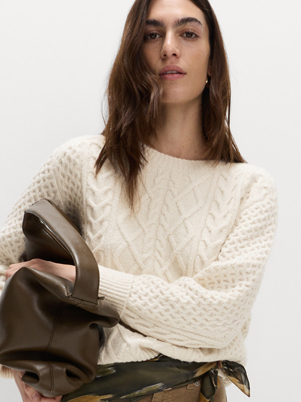 Woman wearing a cream cable-knit jumper