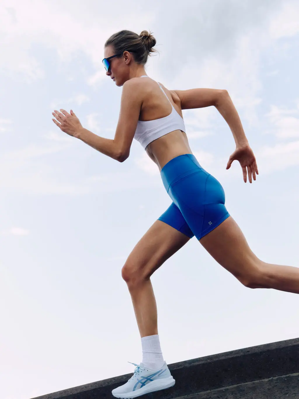 Woman running in a white sports bra and blue shorts