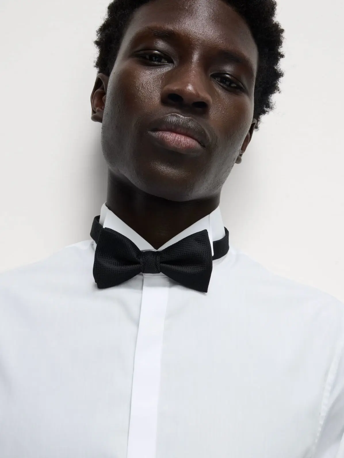 Man wearing white shirt and black bow 