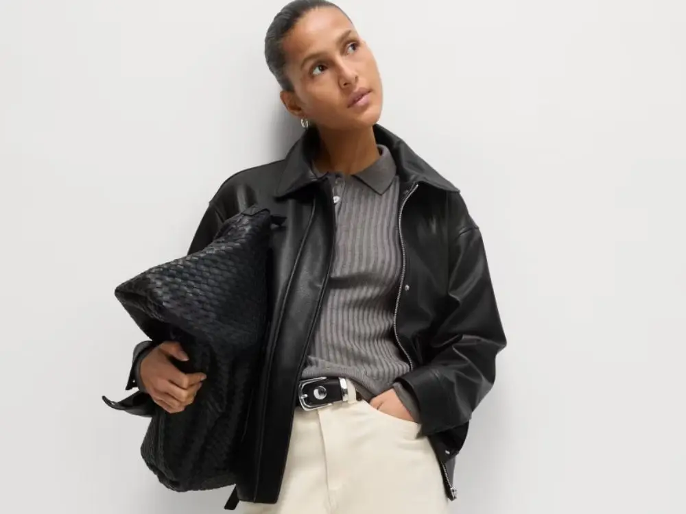 A woman in a faux leather bomber jacet, car