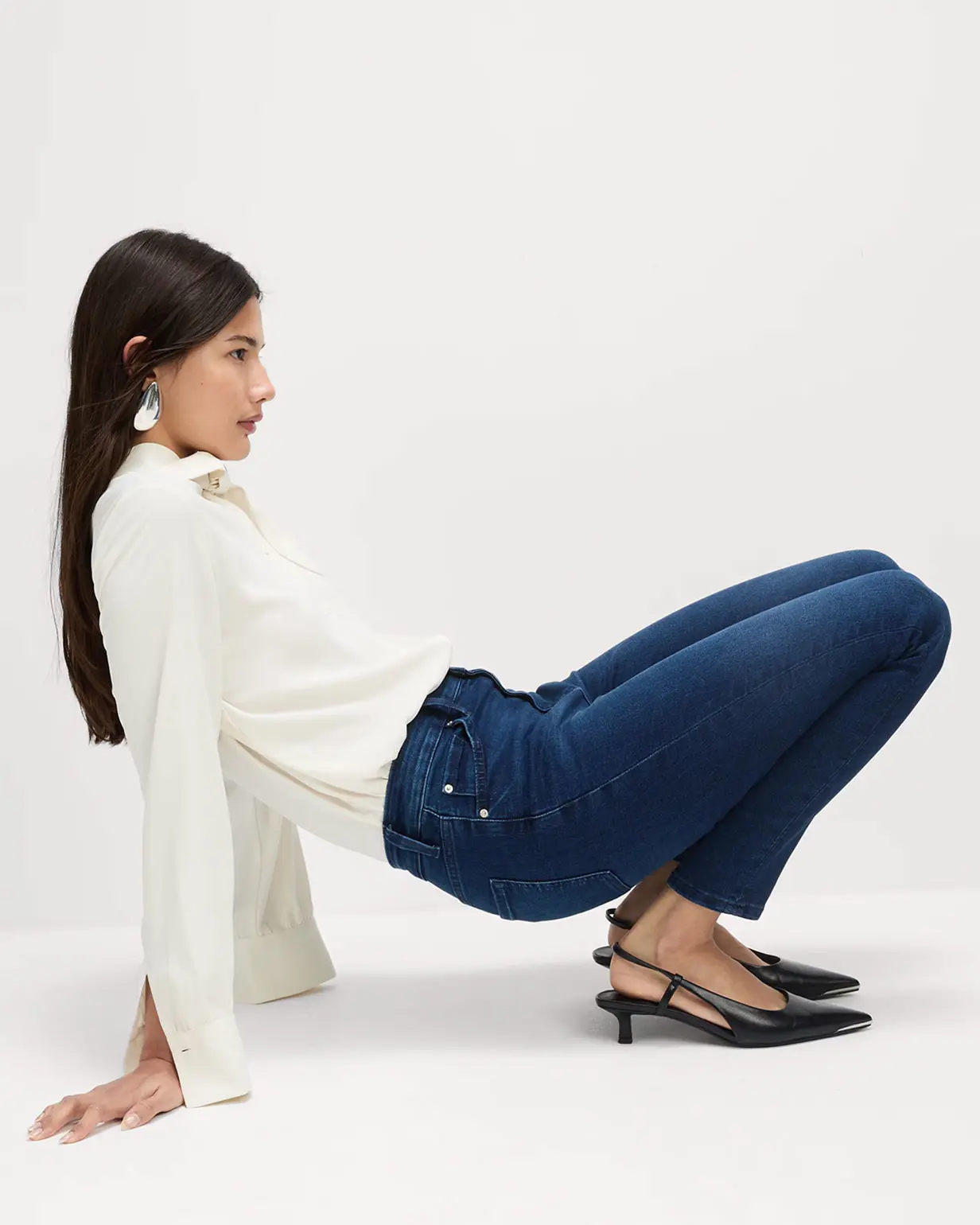 Woman wearing white top, blue skinny jeans and black kitten heels