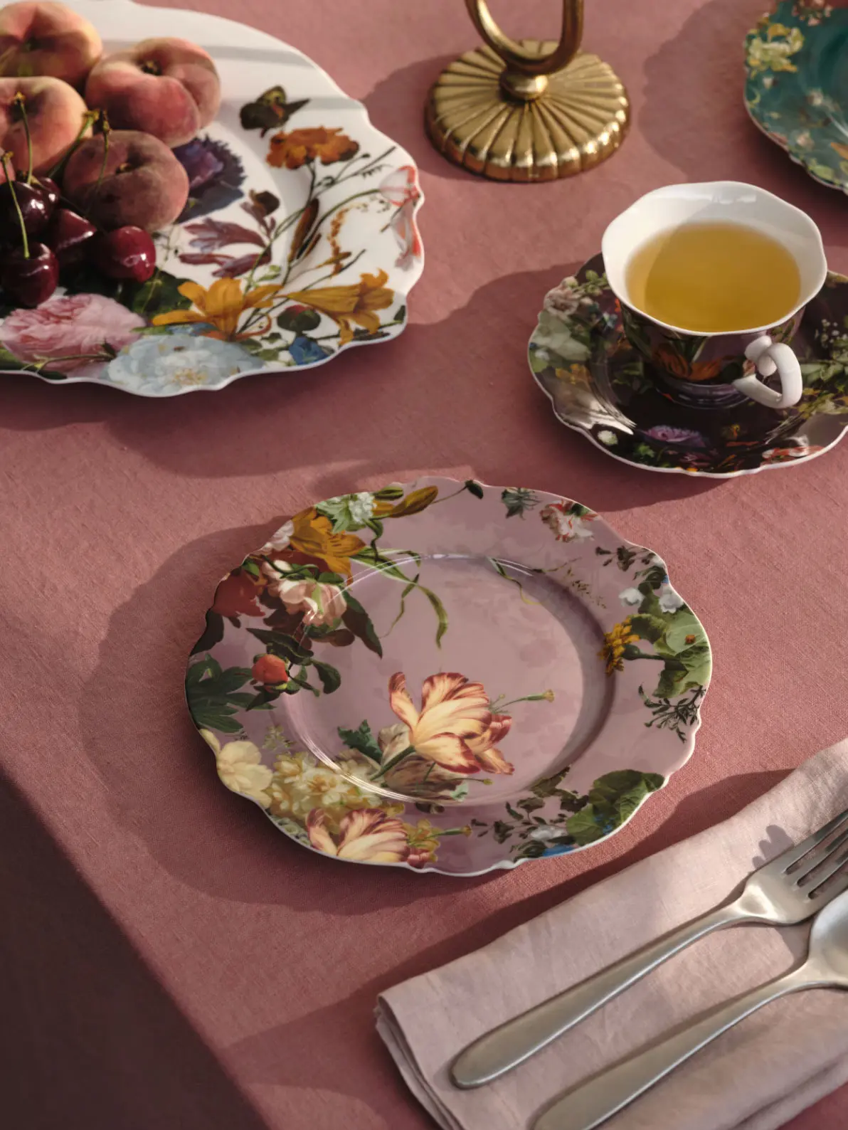 Table setting with floral pink side plates, matching cup and saucer and silver cutlery
