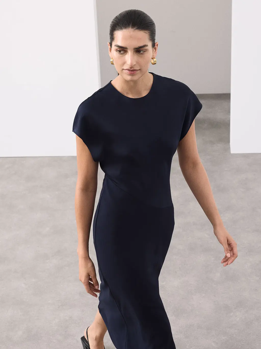 Woman wearing a navy midaxi dress with silver earrings