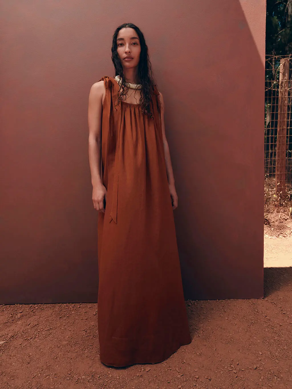 Woman wearing a rust-toned dress with a chunky beaded necklace