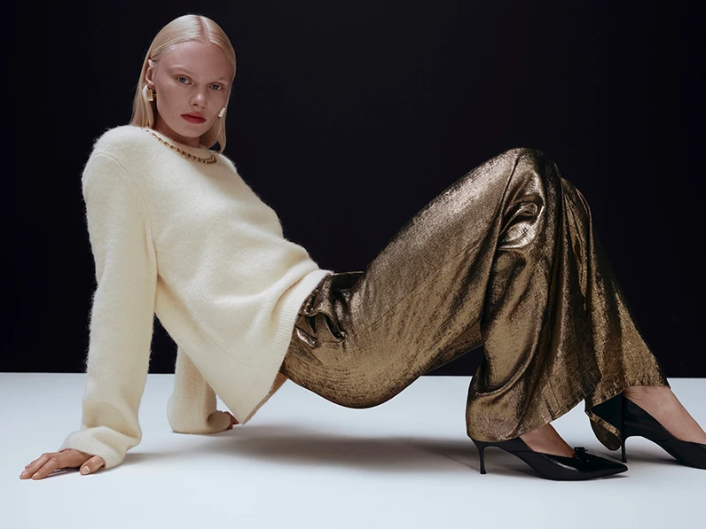 Woman wearing a cream jumper with gold trousers