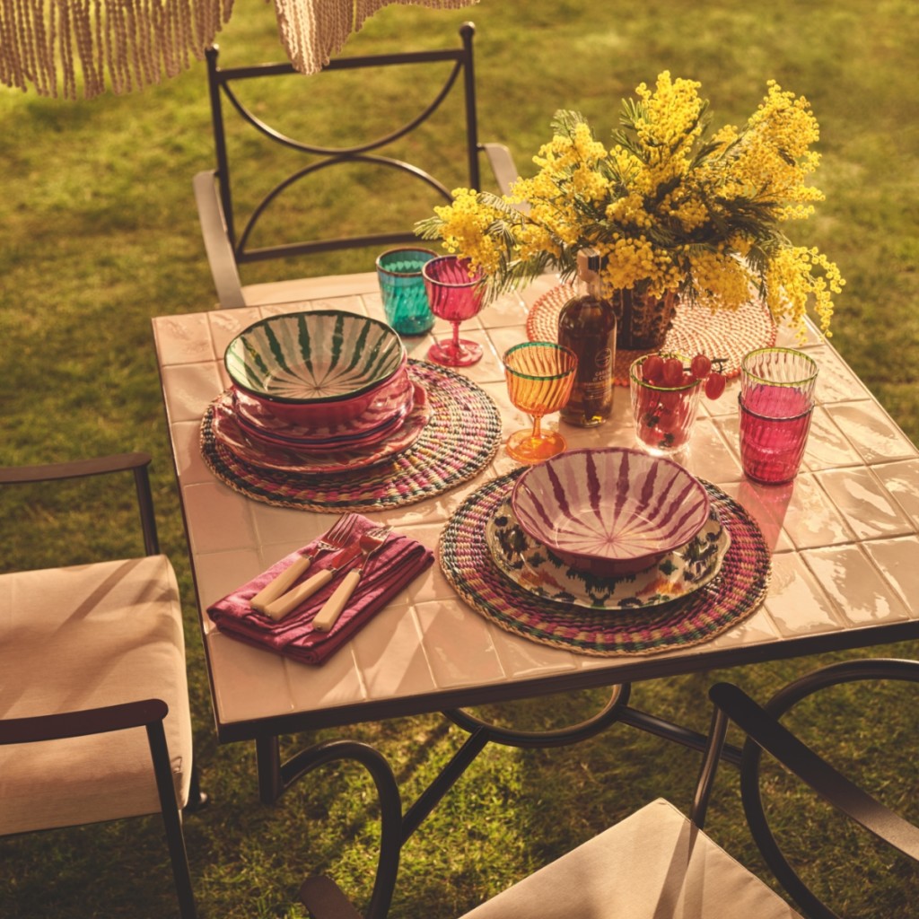 Garden table laid with brightly patterned tableware. Read the feature