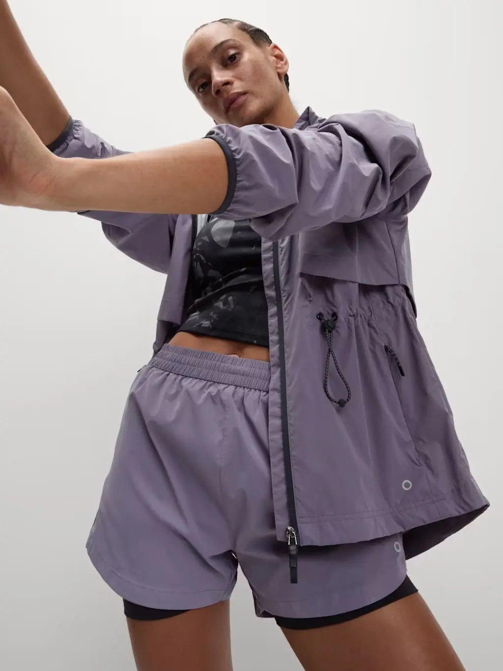 A woman wears lilac layered shorts and matching running jacket
