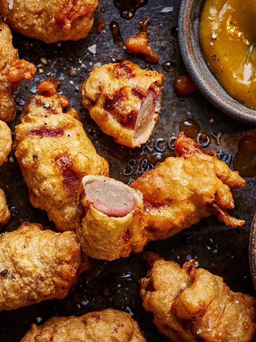 Close up of battered pigs in blankets with curry dipping sauce