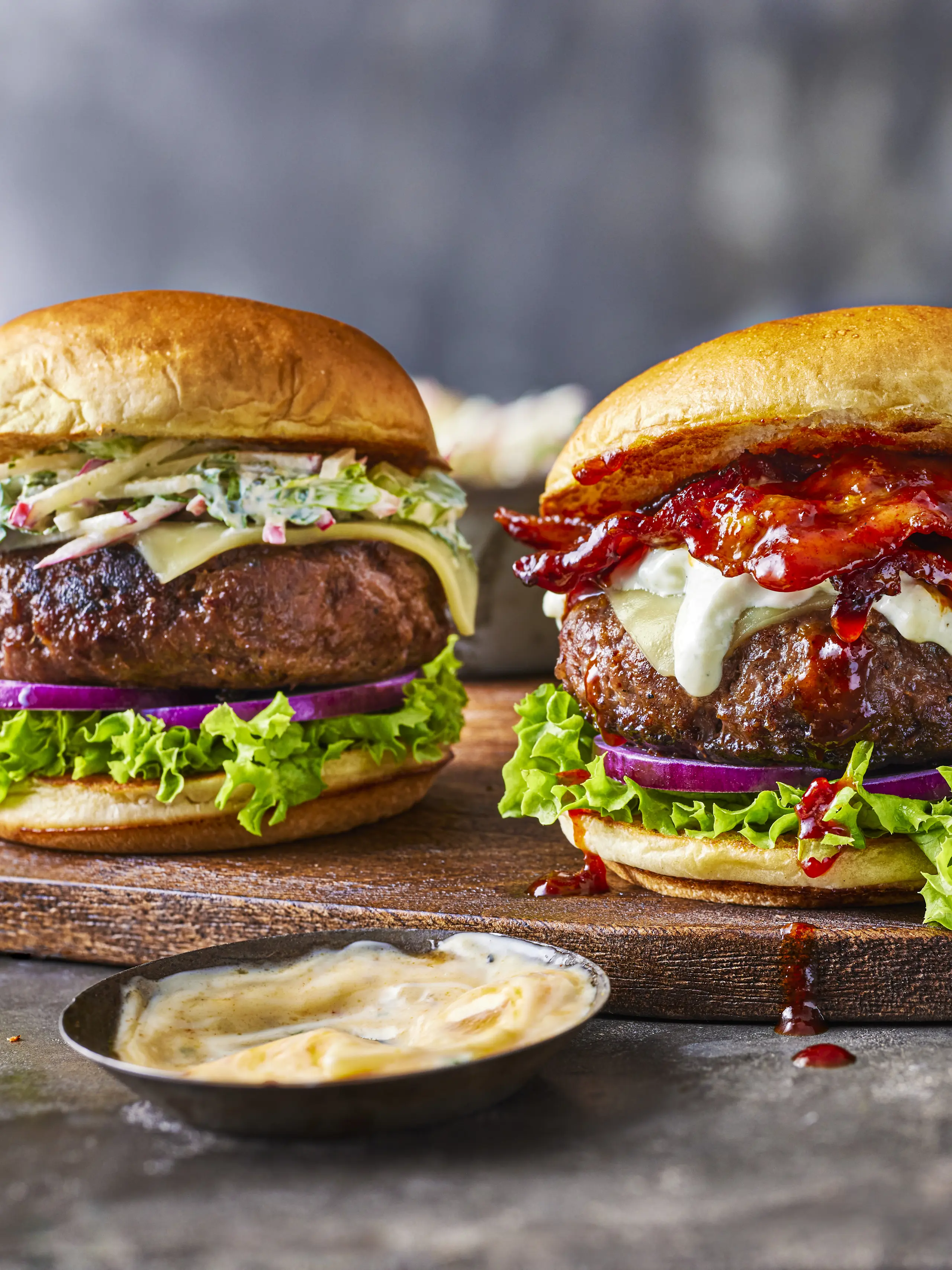 Two burgers with pot of dipping sauce