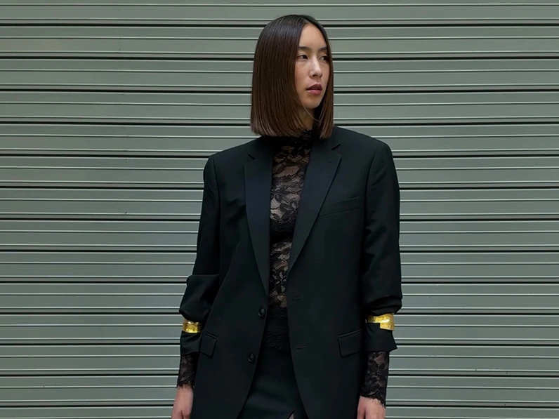 Woman wearing a lace top and black suit jacket.