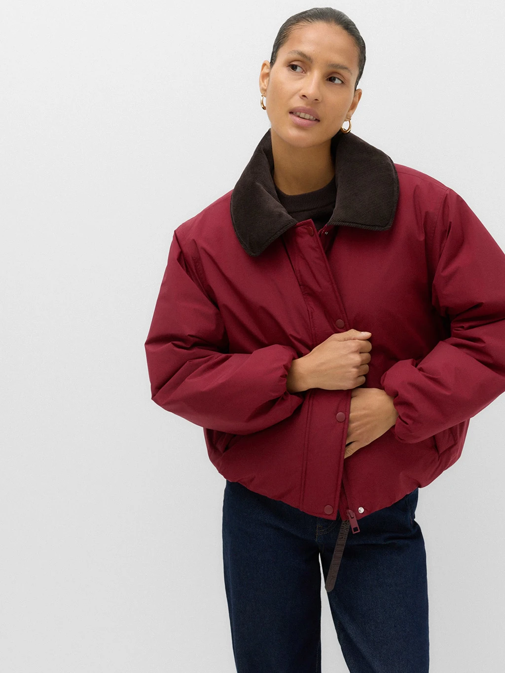 Model wearing a red puffy bomber jacket with a faux fur collar.