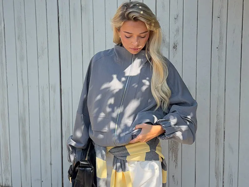 Woman in grey jacket and white trousers