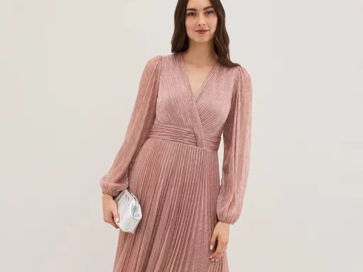 A woman wearing a pink, floor-length, black-tie dress and a silver clutch bag