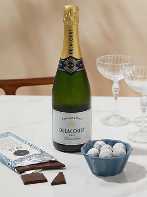 Delacourt champagne bottle with truffles and two champagne glasses. Shop anniversary gifts