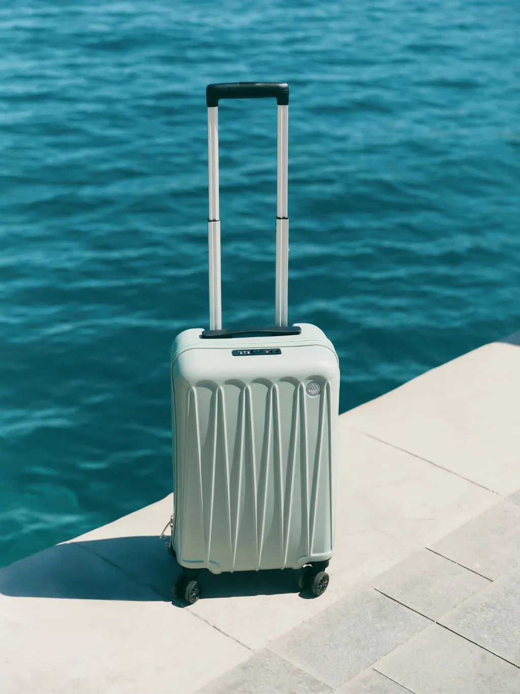 A pale green suitcase sat on the side overlooking the sea