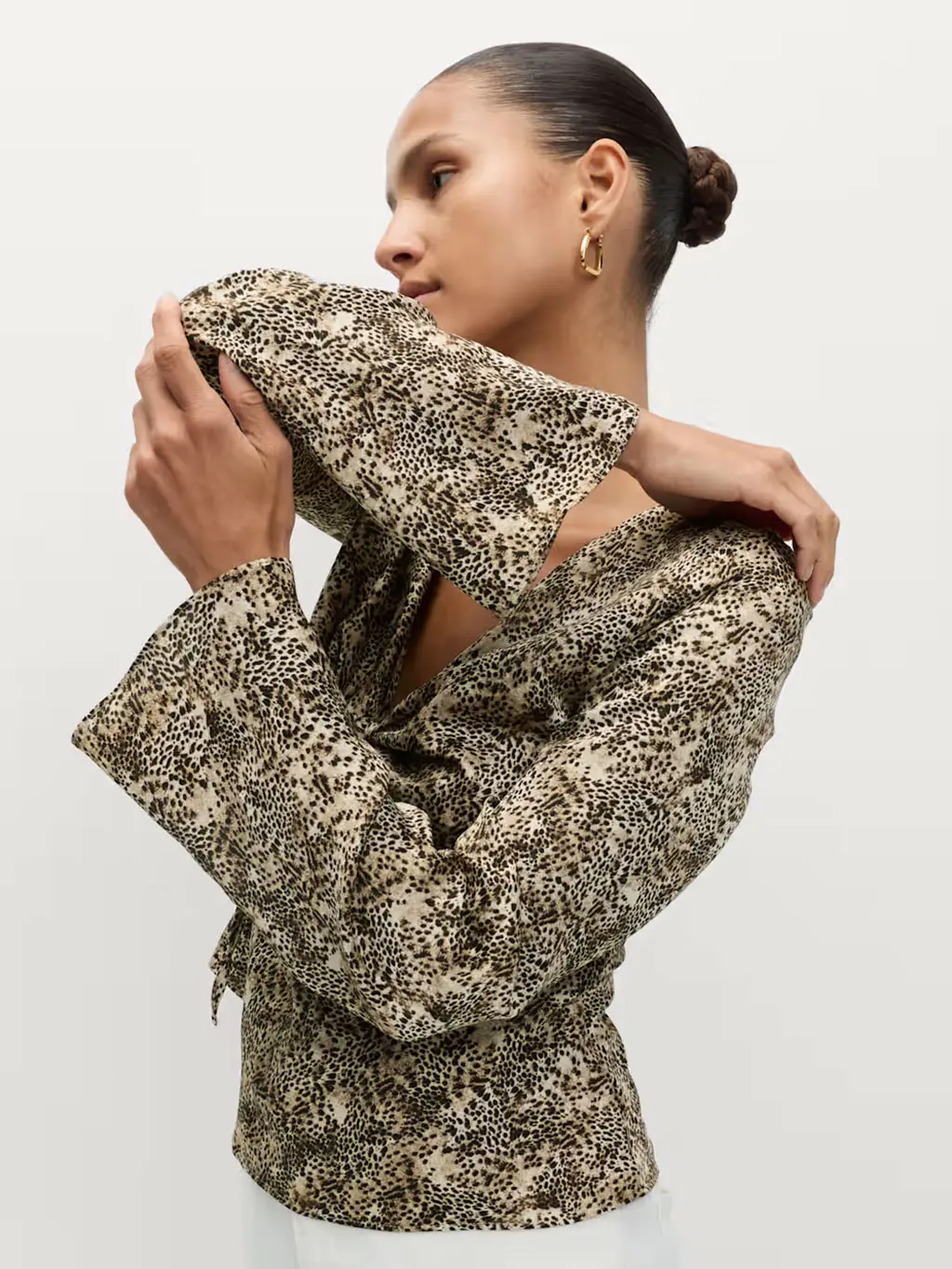 Woman wearing a leopard-print blouse with white jeans and gold jewellery