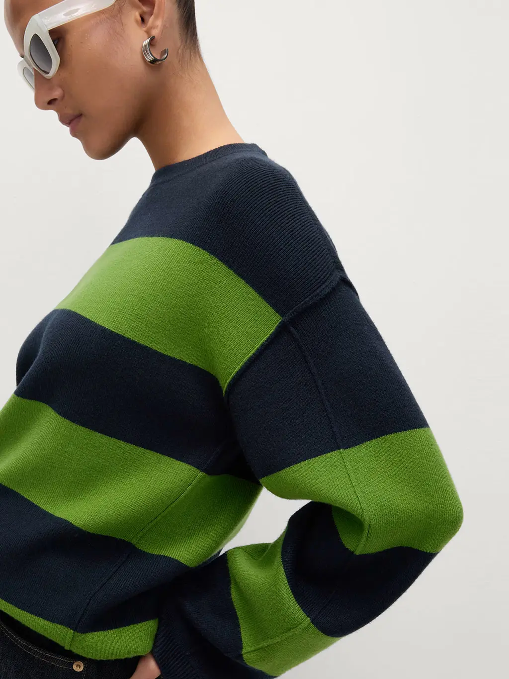 Woman wearing a navy and green striped jumper with white sunglasses