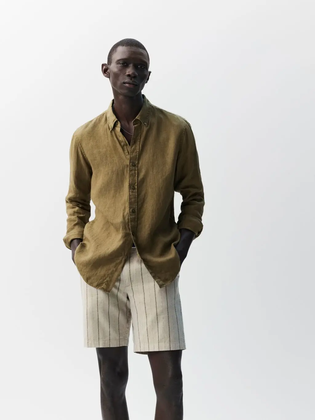 A man wears a khaki linen shirt and stripe linen shorts by M&S