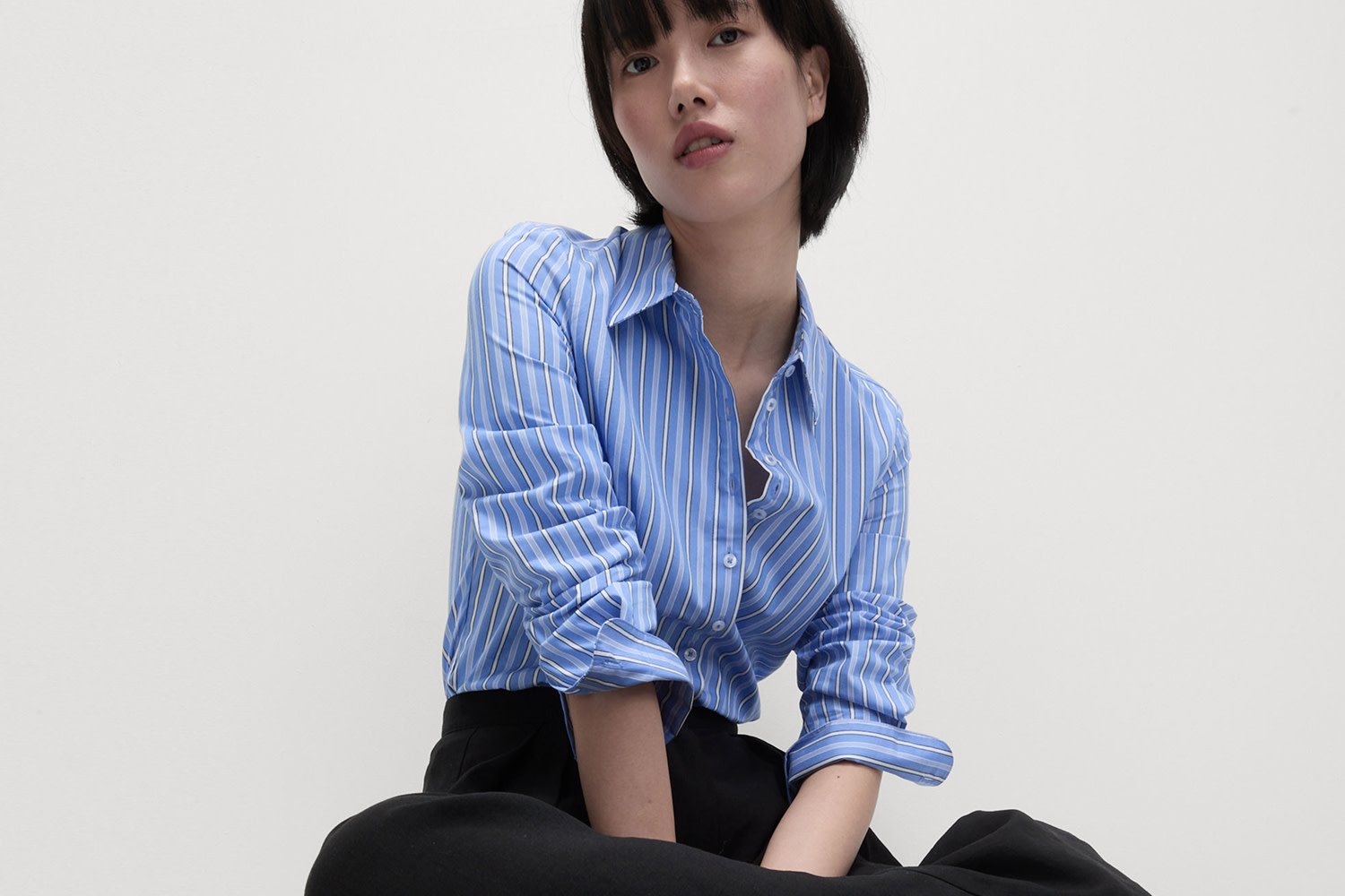 Woman wearing blue striped shirt and black trousers