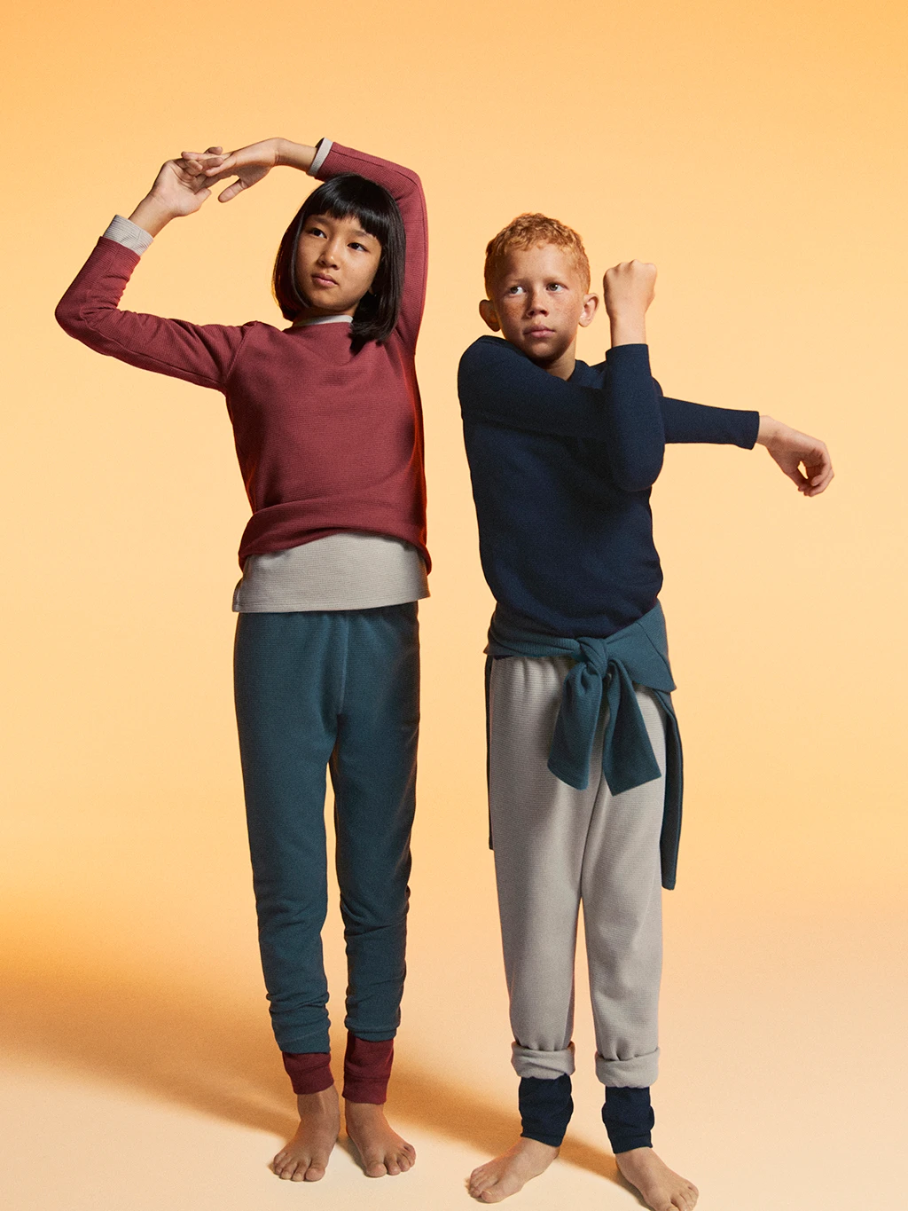 Two children wearing assorted thermal base layers and joggers