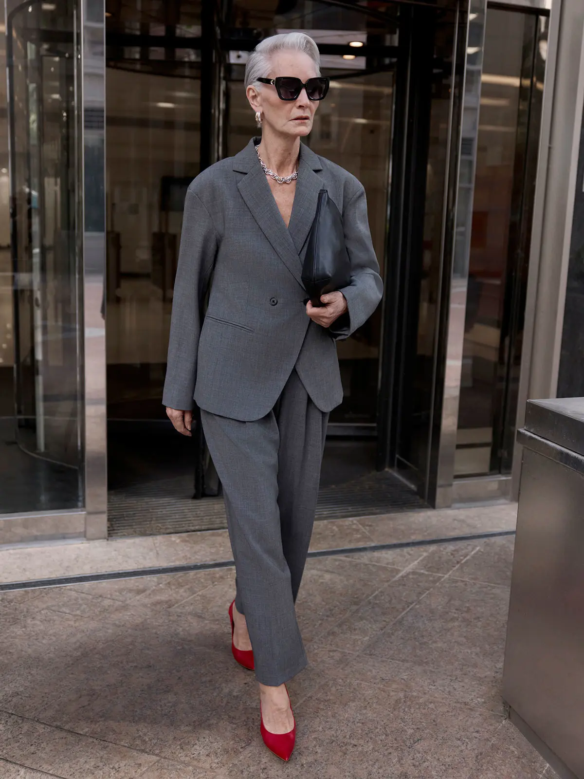 Woman wearing grey suit and red heels 