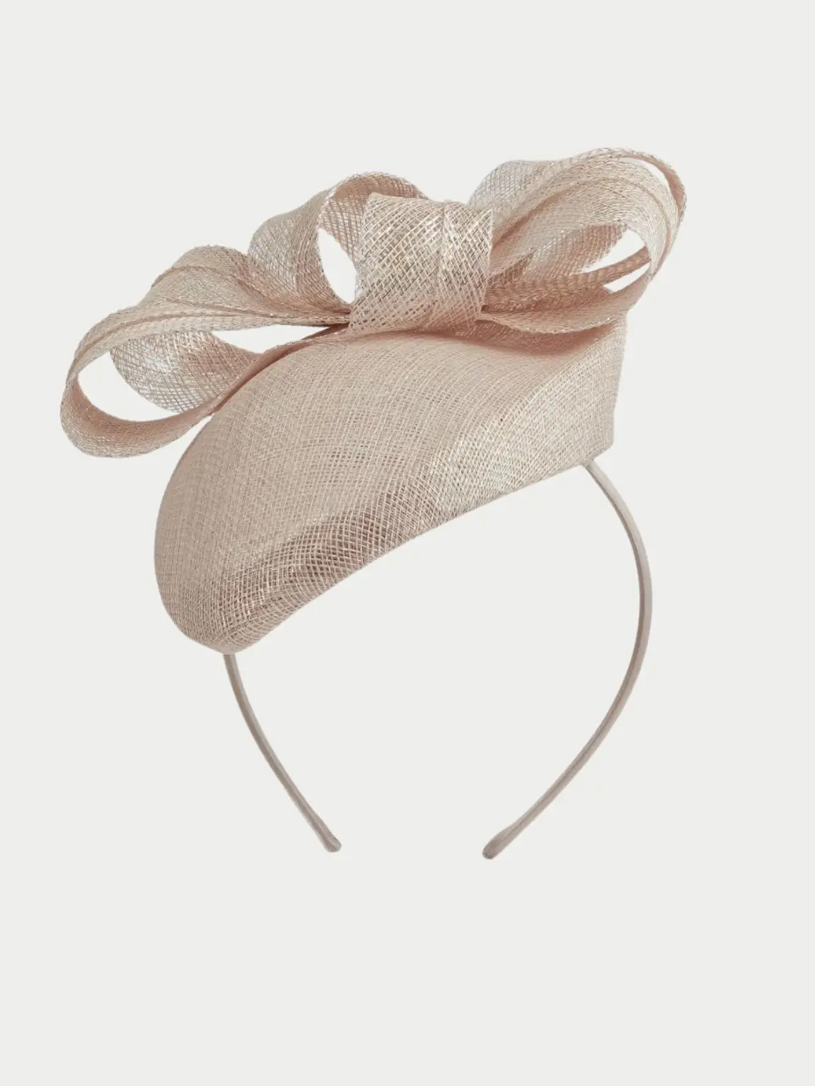 A cut out of a beige fascinator against a pale grey bakcground