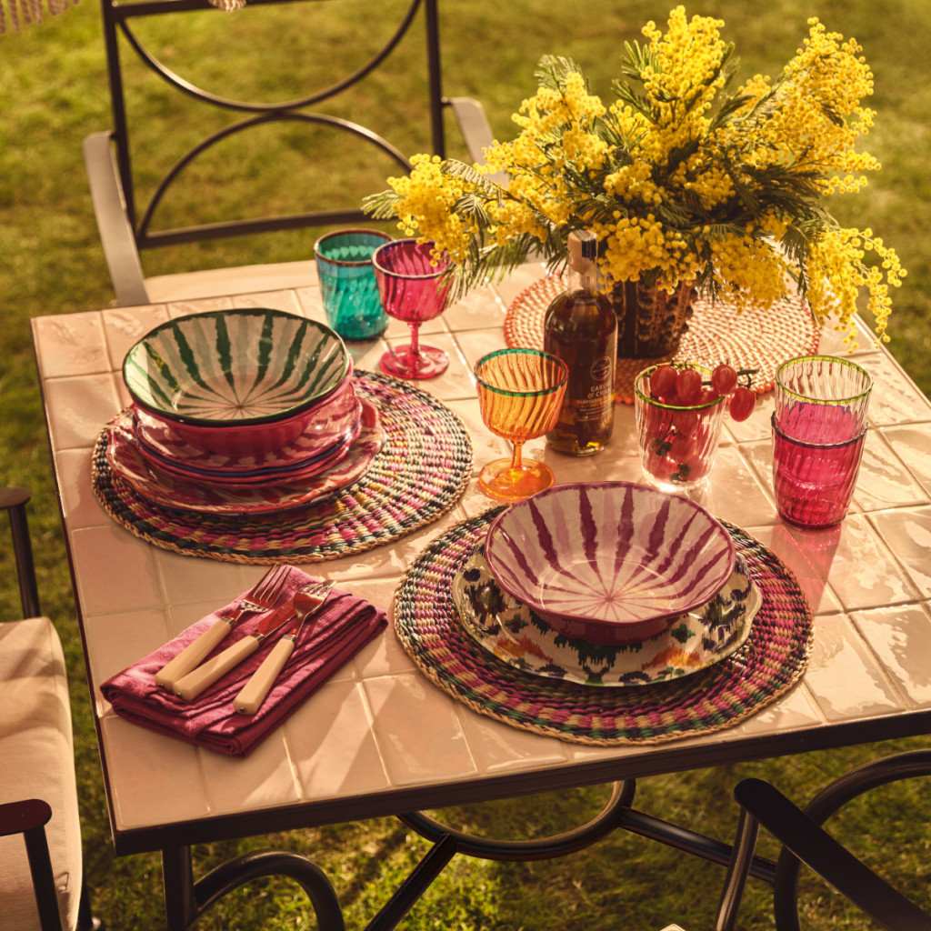 Garden table laid with brightly coloured tableware. Read the feature