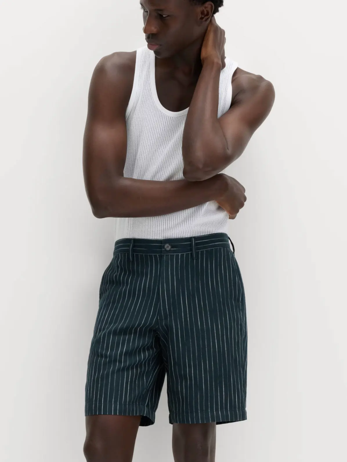 Man wearing white vest and striped navy shorts
