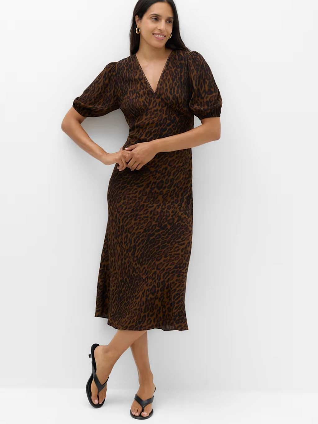 Woman in a midi leopard print brown dress with puff sleeves.