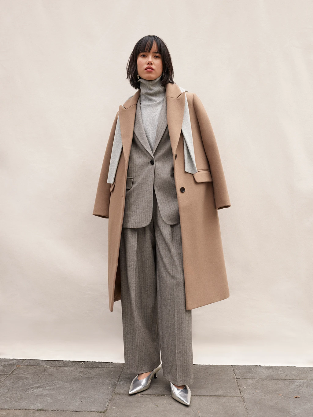 Woman wearing a caramel-coloured tailored longline coat over a grey suit