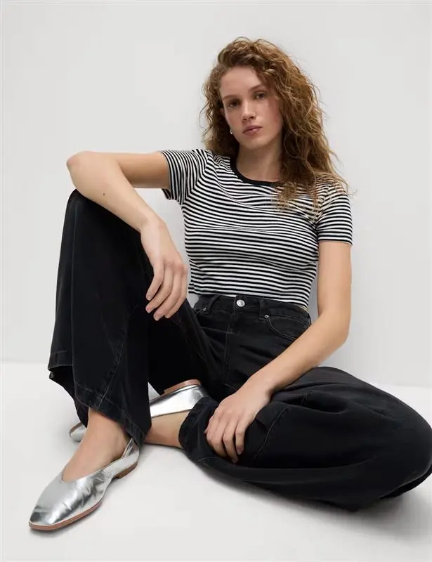 Woman wearing a striped T-shirt with black jeans and silver pumps.
