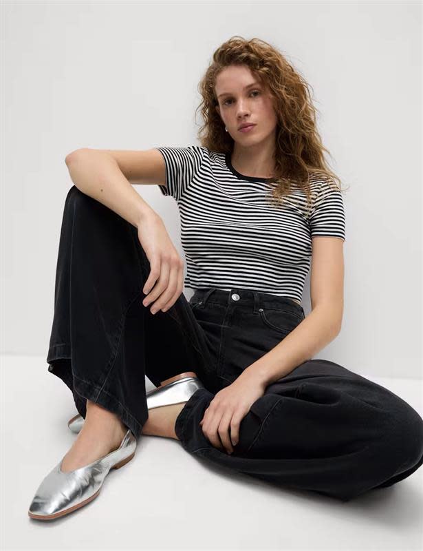 Woman wearing a striped T-shirt with black jeans and silver pumps.
