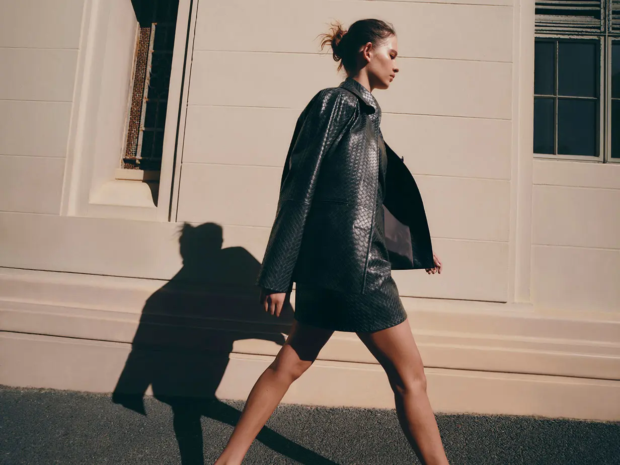 Woman wearing faux leather jacket and matching skirt