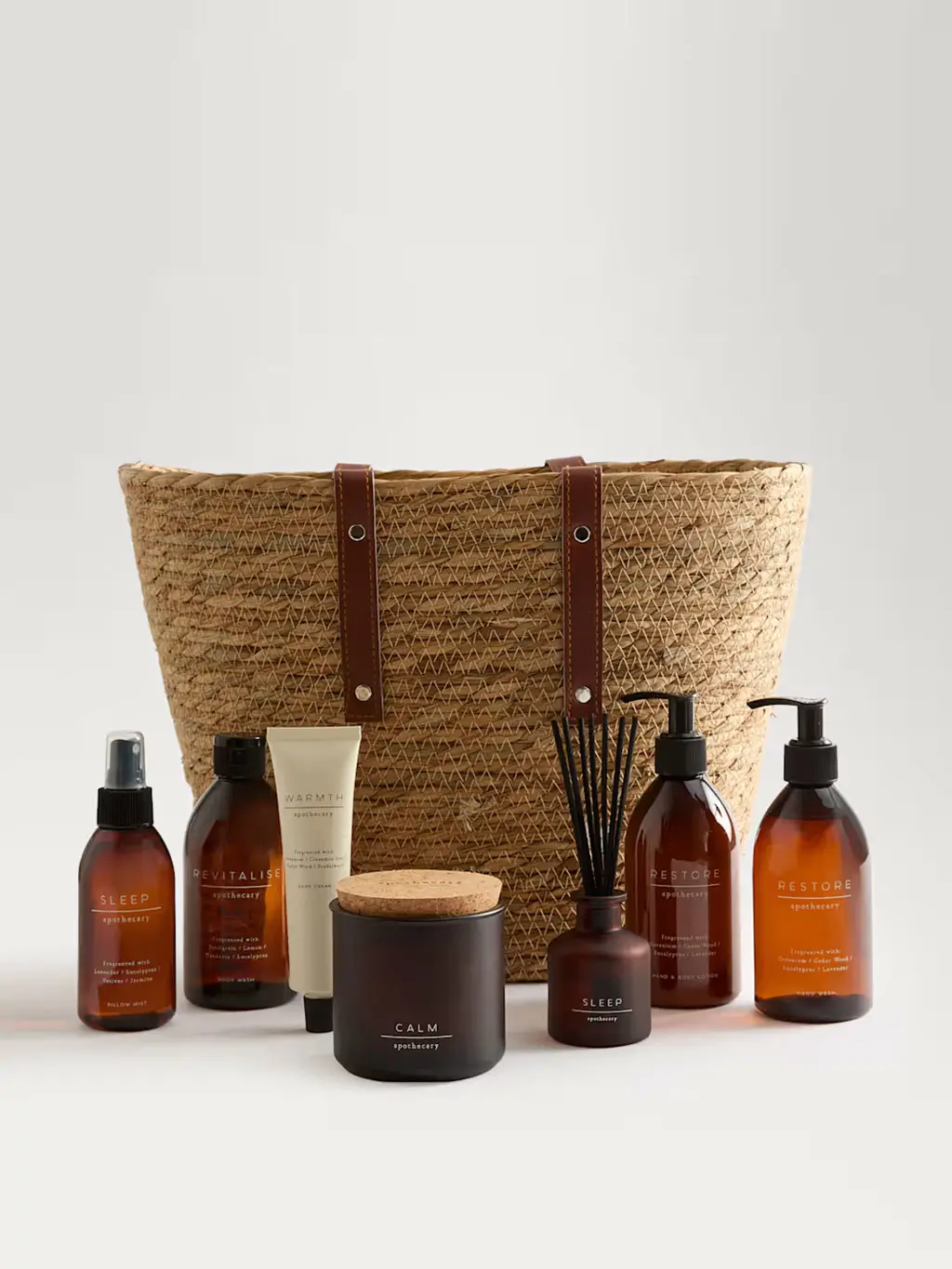 A Revitalise body wash, Restore hand wash, Restore hand and body lotion, Warmth hand cream, Sleep pillow mist, Sleep diffuser and a Calm candle beside in a stylish woven tote bag.