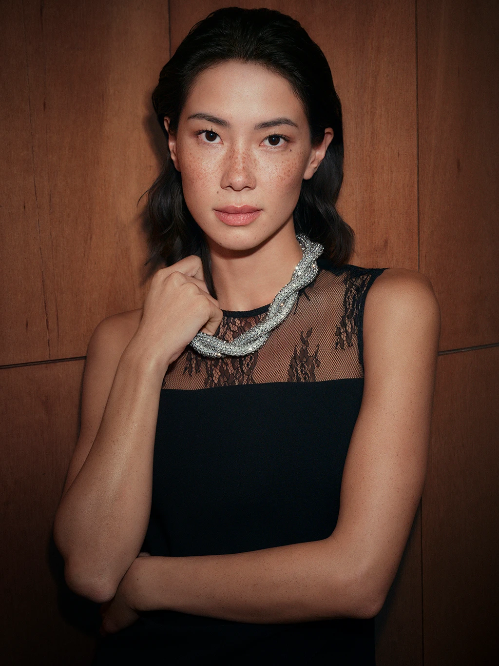 Woman wearing silver twisted necklace with a black lace dress