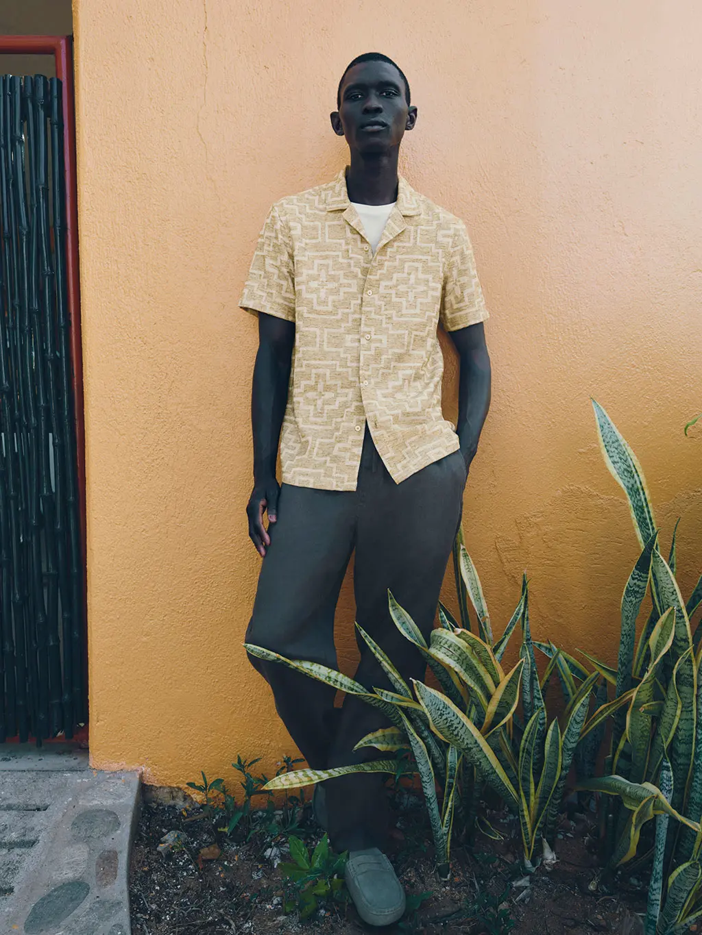 Man in printed shirt against yellow wall