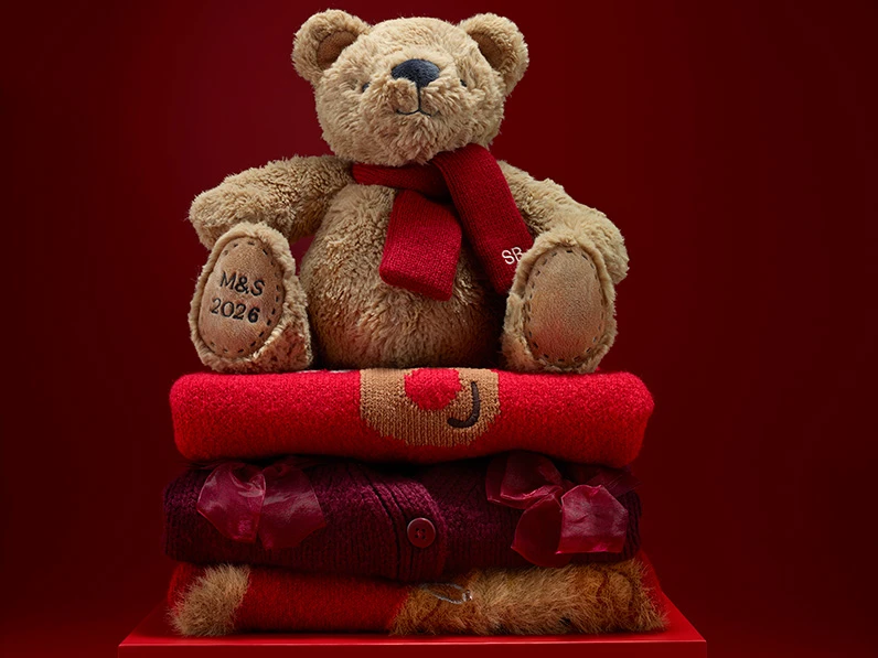 Group of kids' presents including knitted jumpers and a soft teddy bear.