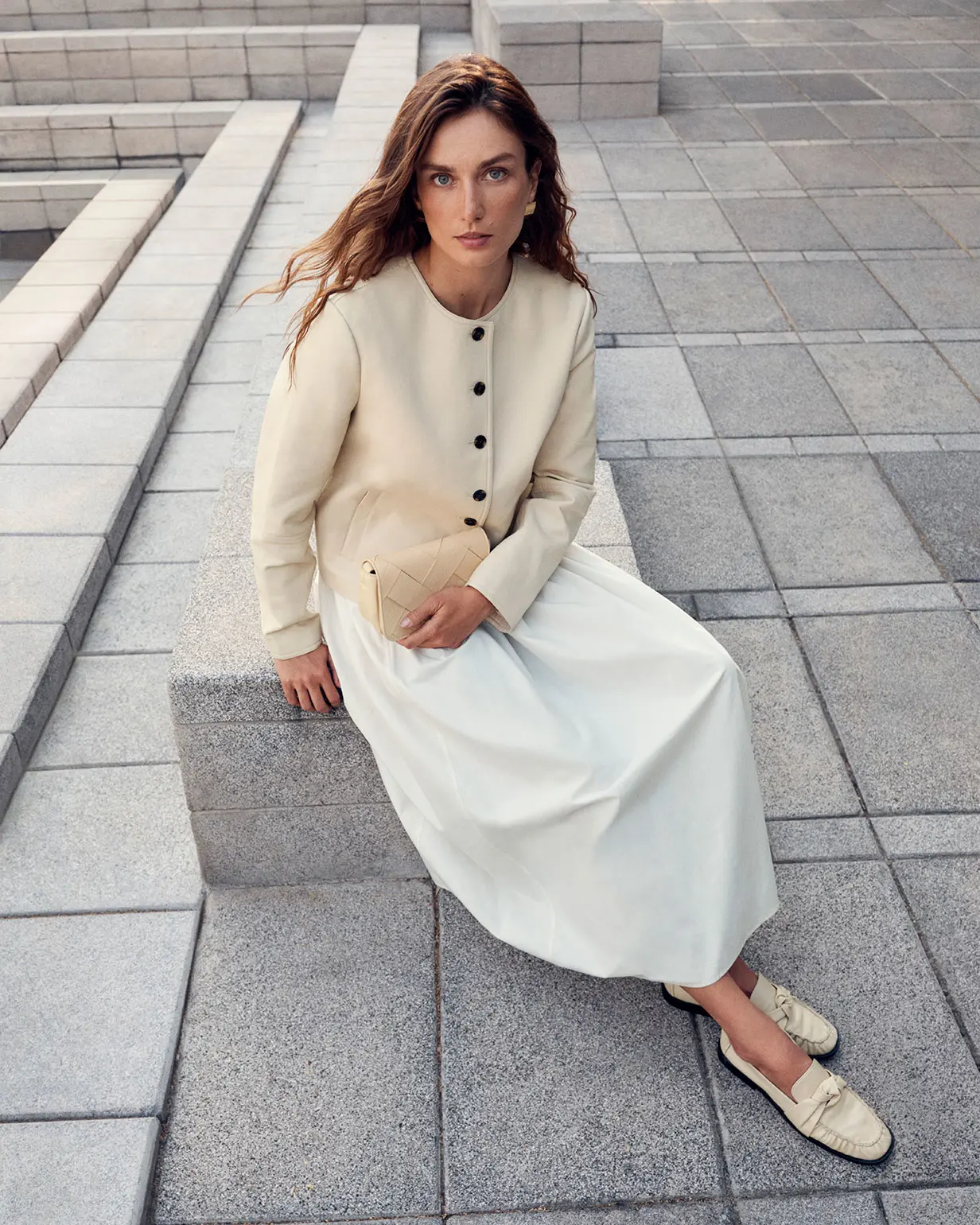 Woman wearing pale yellow faux leather jacket and cream dress