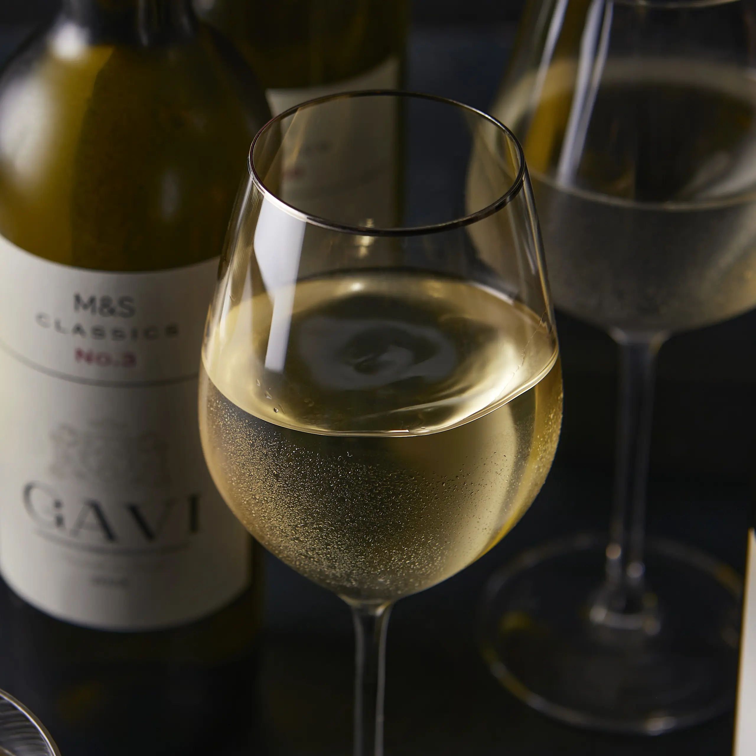 Glass of white wine with bottle in background