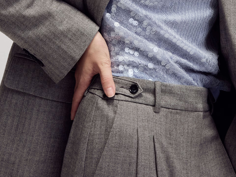 Close-up of herringbone pleated trousers and blue sequin blouse