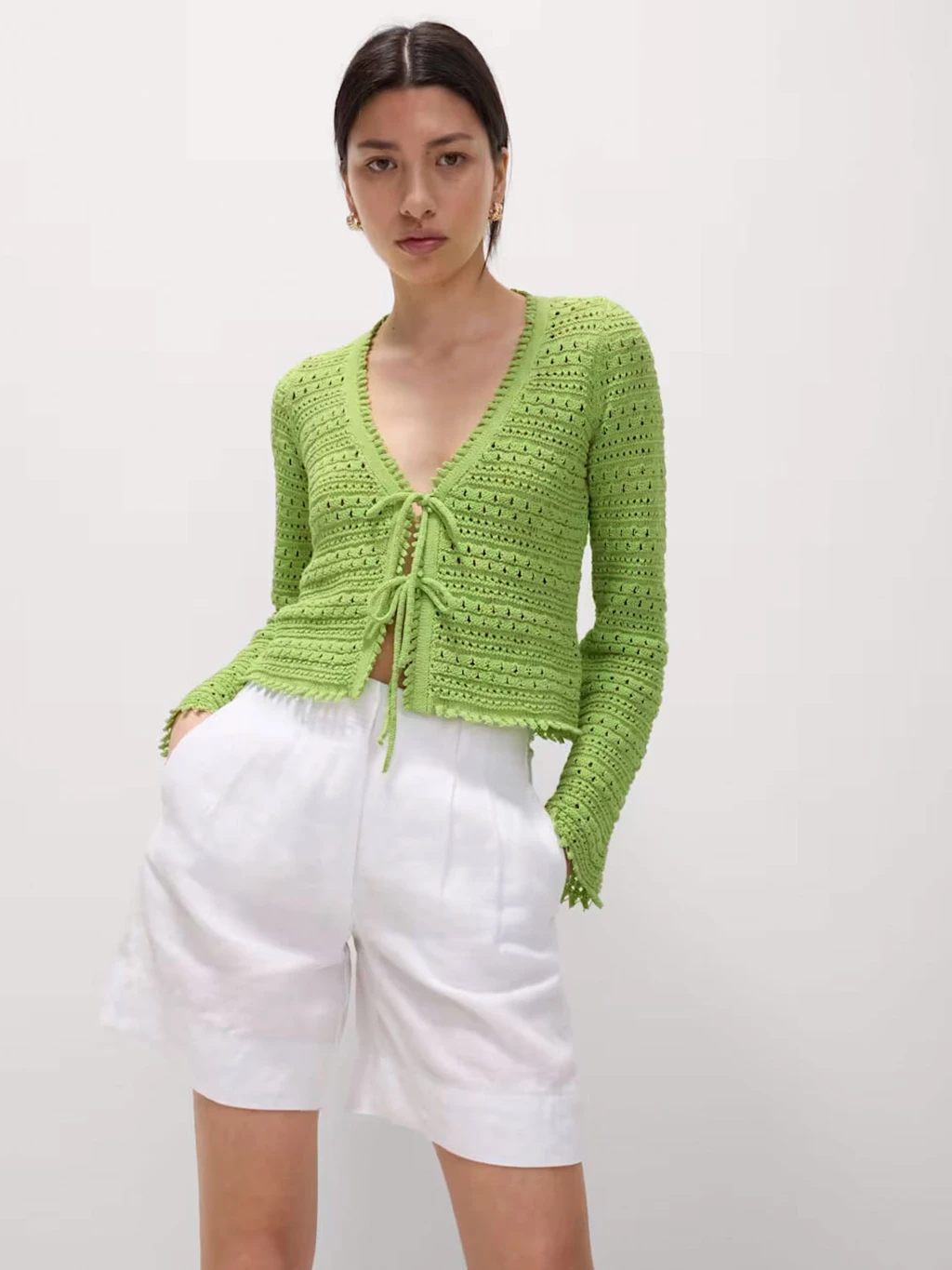 A woman wears a lime-green tie-front top with white shorts