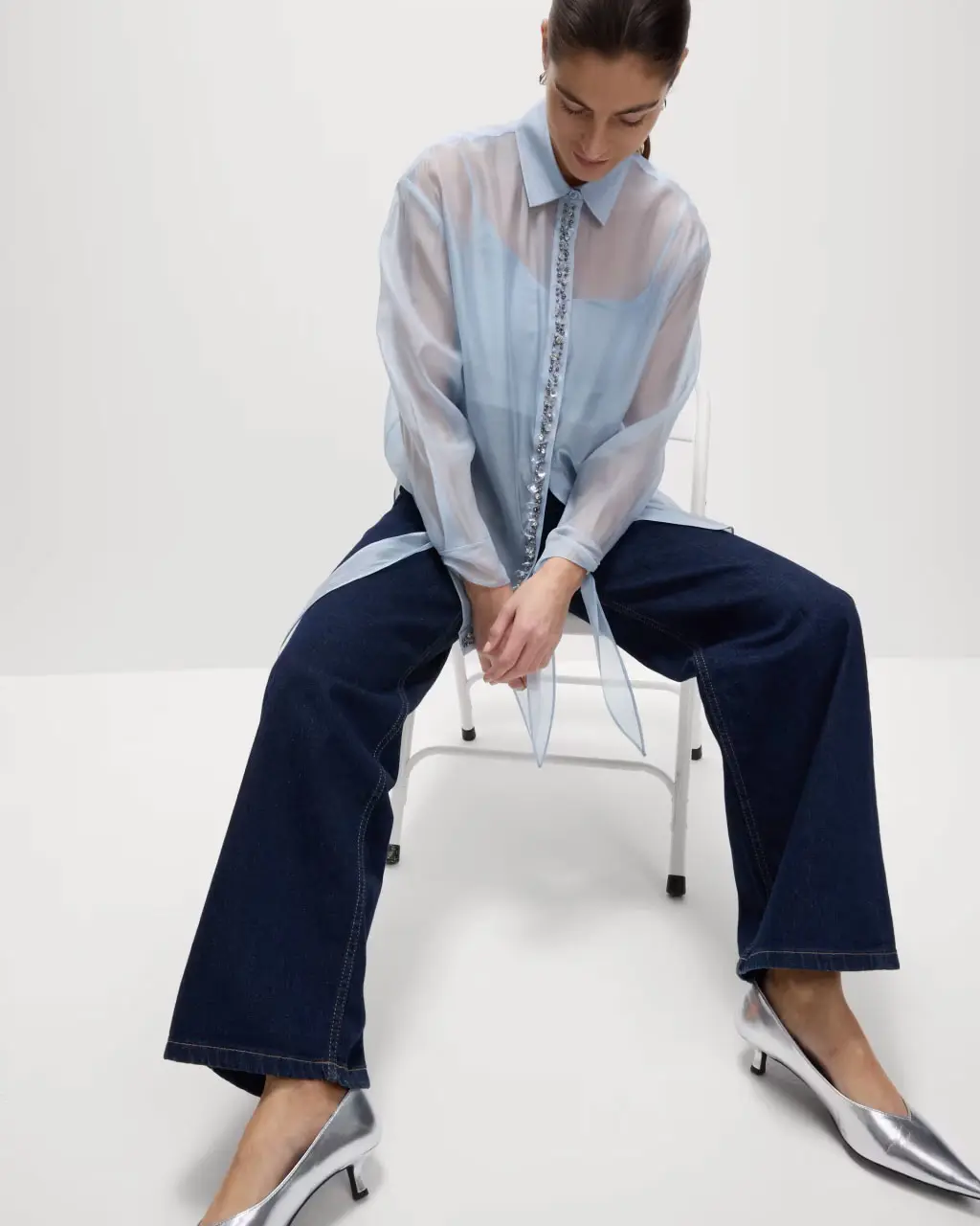 Woman wearing pale blue sequinned blouse. 