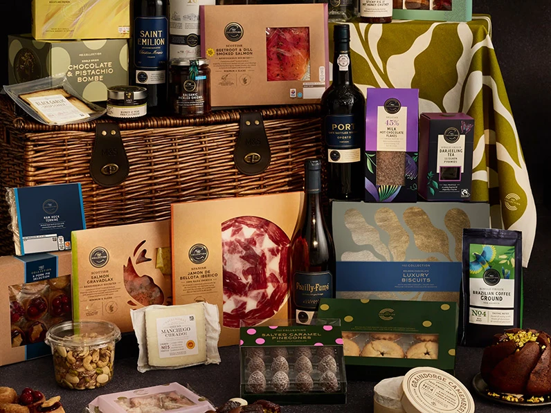 Group of M&S products in a wicker hamper, with wine, cheese and crackers.
