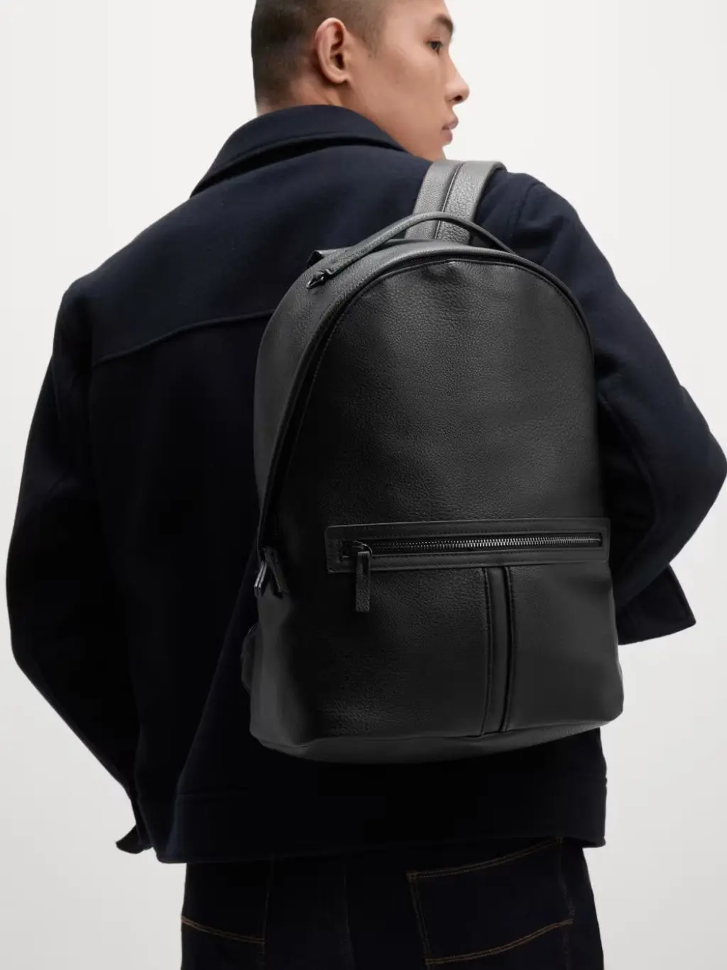 A man carries a black and grey backpack from M&S